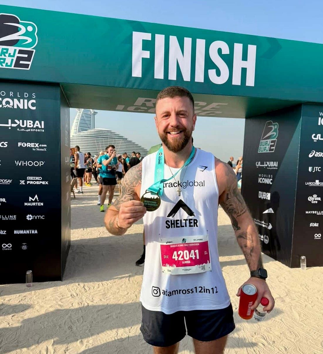 Adam Ross at the finish line of the Dubai Half Marathon in his Shelter and Track Global running vest